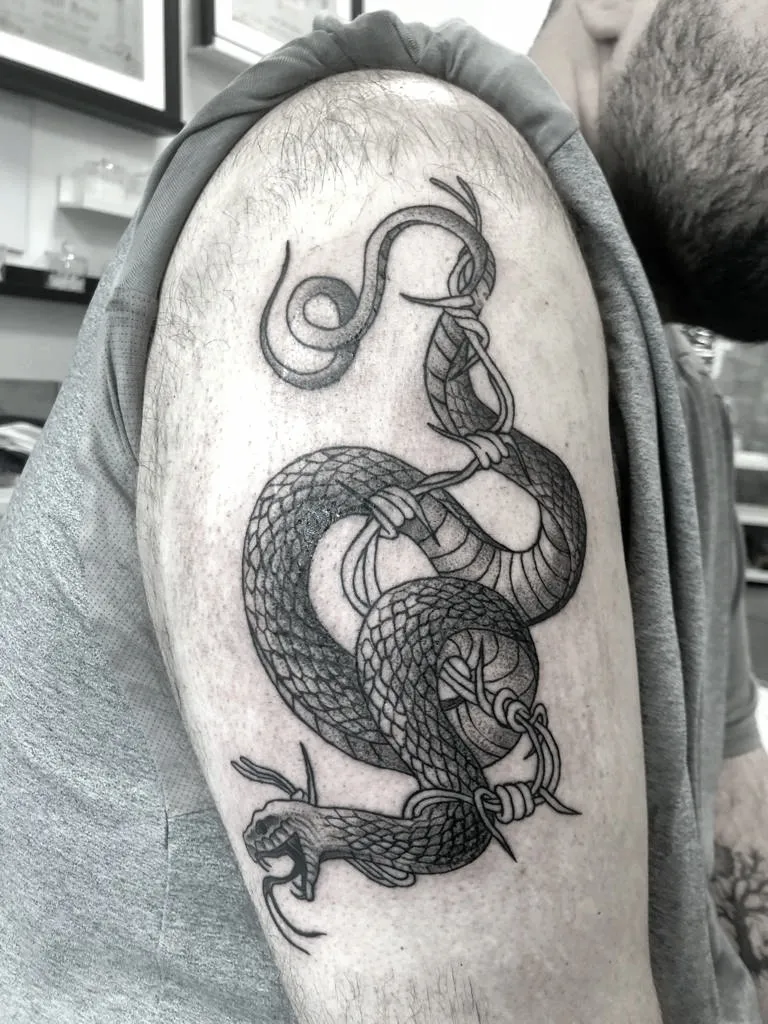 Tatuaggio bianco e nero di un serpente con la bocca aperta